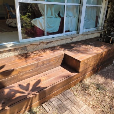 ספסל עץ בגינה ליד חלון זכוכית גדול