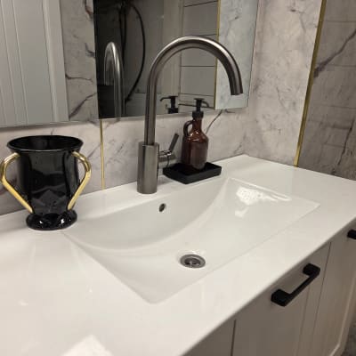 כיור עם ברז מודרני וחפצים נוספים בחדר אמבטיה