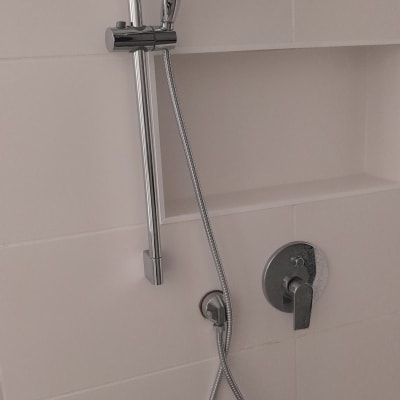 ראש מקלחת וכפתור מים על קיר אמבטיה