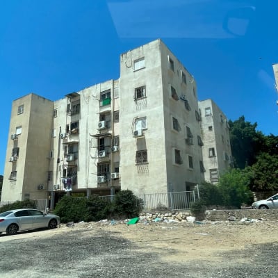 בניין מגורים עם מכוניות וחצר לא מטופחת