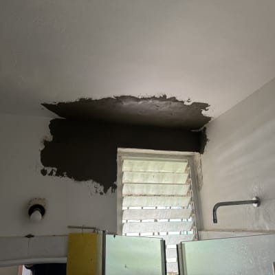 עבודת תיקון וטיוח בתקרה ובקיר בחדר רחצה במהלך שיפוץ
