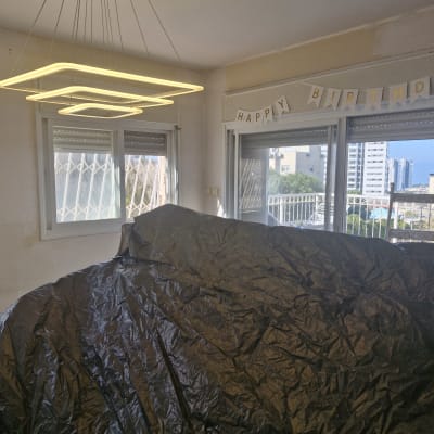 כיסוי פלסטיק שחור על רהיטים בחדר לקראת צביעה