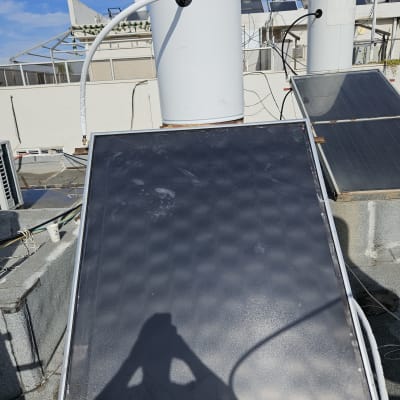 דוד שמש עם קולטים על גג תחת שמיים כחולים