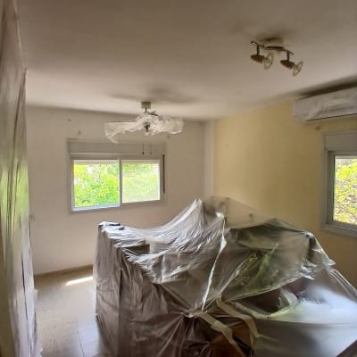 חדר עם רהיטים מכוסים בניילון לקראת צביעה