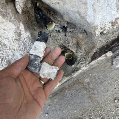 יד מחזיקה צינור שבור ליד קיר