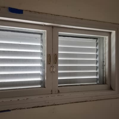 חלון עם תריסים סגורים בתוך מסגרת לבנה