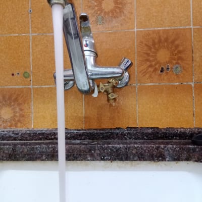 ברז מים זורם בכיור עם אריחים כתומים