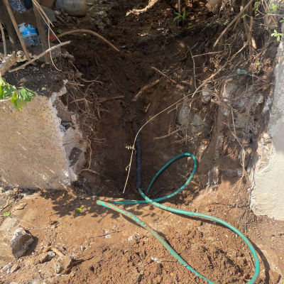 חפירה באדמה עם צינור ירוק וכבל חשמל שחור