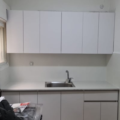 מטבח חדש עם ארונות לבנים וכיור נירוסטה.