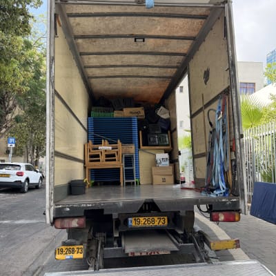משאית פתוחה עם ציוד הובלה ברחוב עירוני