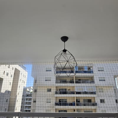 גוף תאורה מעוצב ורשת הגנה מותקנים במרפסת דירה