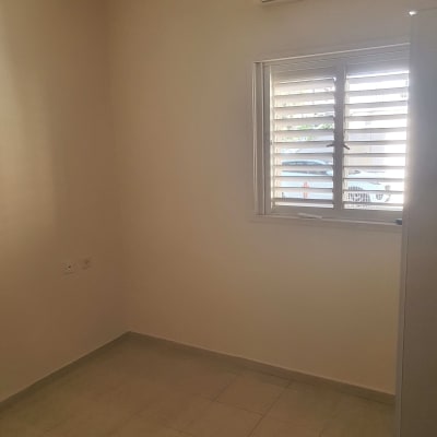 חדר ריק עם מזגן על הקיר וחלון עם תריסים