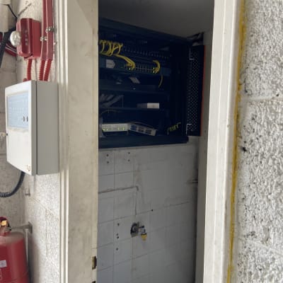 ארון תקשורת עם כבלים וציוד רשת בחדר קטן