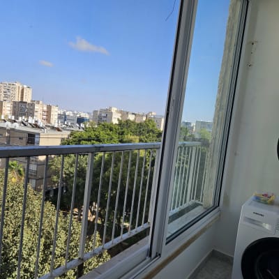 חלון אלומיניום עם נוף עירוני ומכונת כביסה