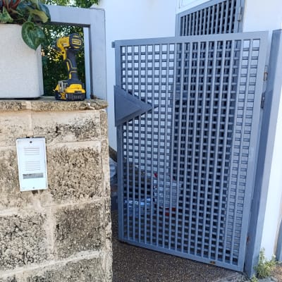 אינטרקום מותקן על קיר אבן ליד שער מתכת