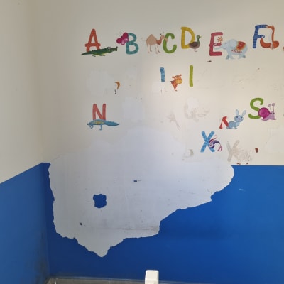 קיר עם קילופי צבע ואותיות צבעוניות, מתאים לתיקוני בית.