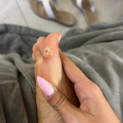 יד עם ציפורניים מטופחות מחזיקה כף רגל