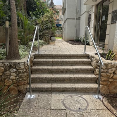 מעקה מתכת לצד מדרגות אבן בכניסה לבניין