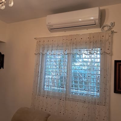 מזגן מותקן מעל חלון עם וילון בסלון