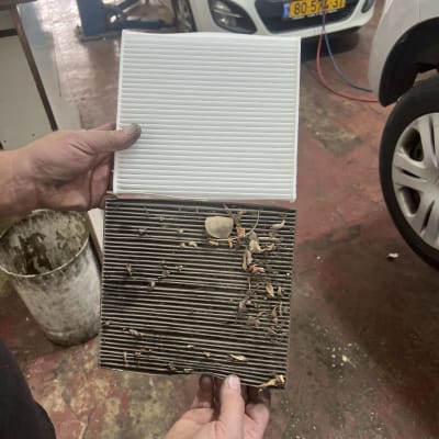 פילטר אוויר ישן ומלוכלך ופילטר חדש ונקי מוחזקים בידיים במוסך