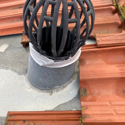 צינור מתכת עם כיסוי מגן על גג רעפים אדום