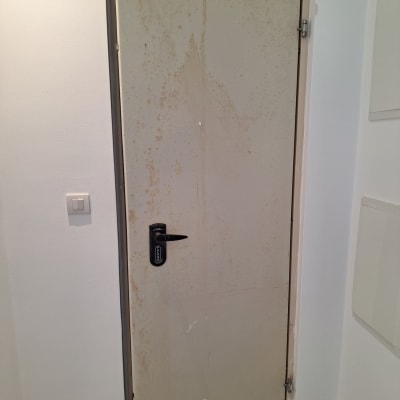 דלת מתכת עם ידית שחורה וקיר לבן