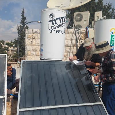 אנשים מתקנים דוד שמש על גג עם קולטים