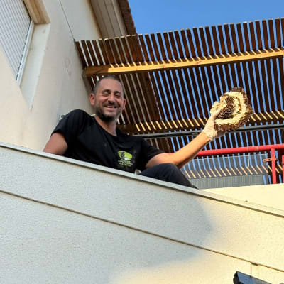 אדם מחזיק קן דבורים על גג בית