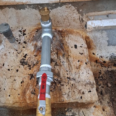 צינור מים עם שסתום על רקע קיר בטון
