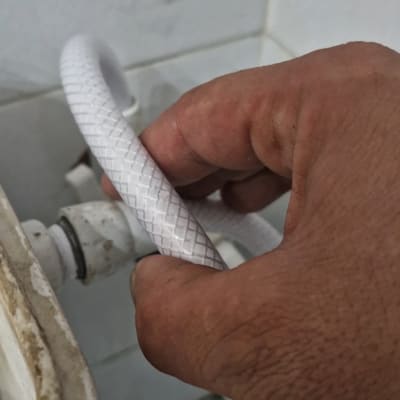 יד מחזיקה צינור לבן ליד חיבור צנרת