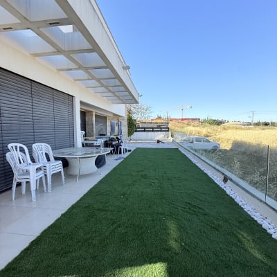 דשא סינתטי על מרפסת עם כיסאות פלסטיק ושולחן