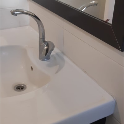 כיור עם ברז חדש ומראה במסגרת כהה