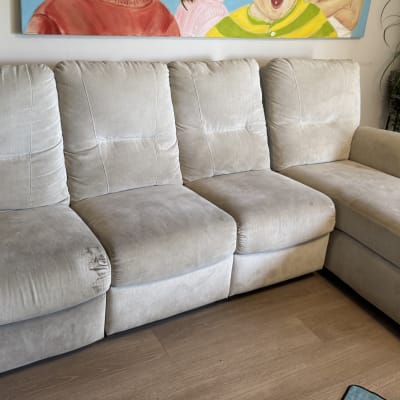 ספה אפורה עם כתמים על רצפת עץ