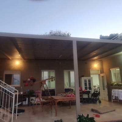 פרגולה מאלומיניום מחוברת לבית עם תאורה
