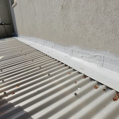 איטום גג עם חומר לבן ליד קיר חיצוני