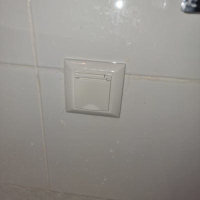 שקע חשמלי עם כיסוי על קיר אריחים