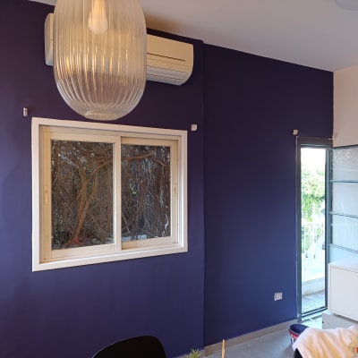 קיר צבוע בצבע סגול כהה עם חלון ודלת פתוחה