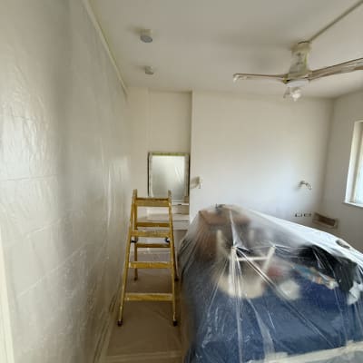 חדר עם סולם וציוד מכוסה בניילון לקראת צביעה