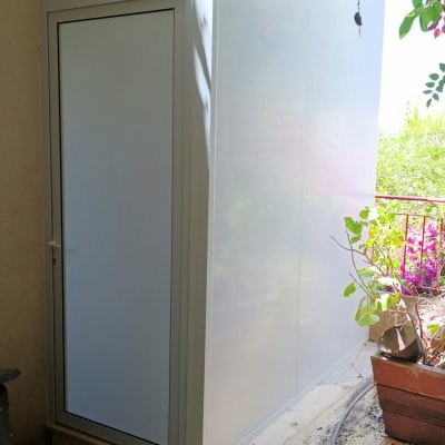 מבנה אלומיניום עם דלת ליד צמחייה