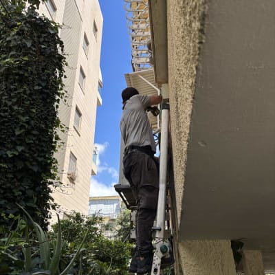 אדם על סולם מתקין מזגן על קיר חיצוני