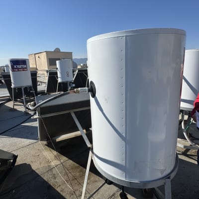 דוד שמש לבן על גג עם צינורות וחיבורים