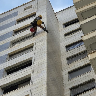 אדם עם קסדה מטפס על קיר בניין גבוה