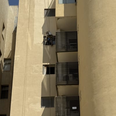 אדם עובד בגובה על בניין עם חבלים