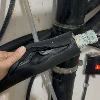 צינור פגום עם בידוד שחור ומחבר מתכת