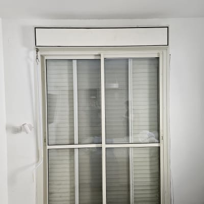 תריסים סגורים על חלון זכוכית עם מסגרת לבנה