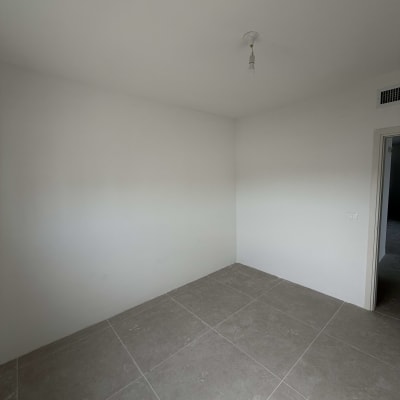 חדר ריק עם קירות צבועים ורצפת אריחים אפורה