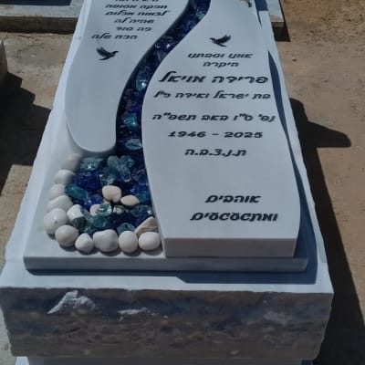 מצבה עם כיתוב בעברית ואבנים צבעוניות