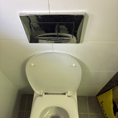 אסלה עם לחצן הדחה על קיר לבן