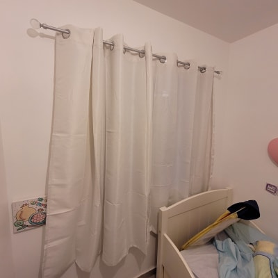 וילון לבן תלוי על מוט מתכת בחדר ילדים