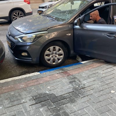 רכב אפור חונה לצד המדרכה עם דלת פתוחה